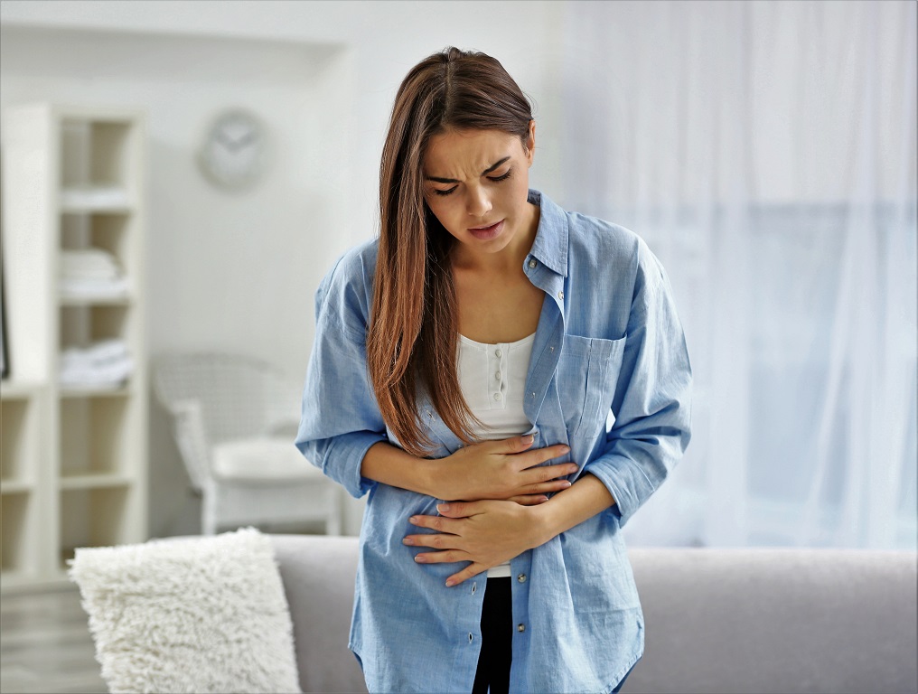Young woman suffering from abdominal pain at home. Gynecology concept